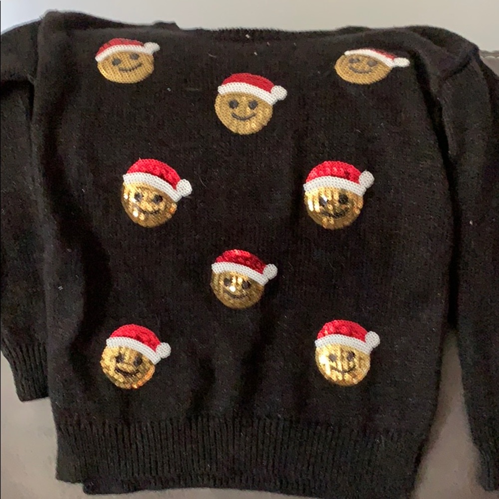 A smiley emoji Christmas sweater with tags on.